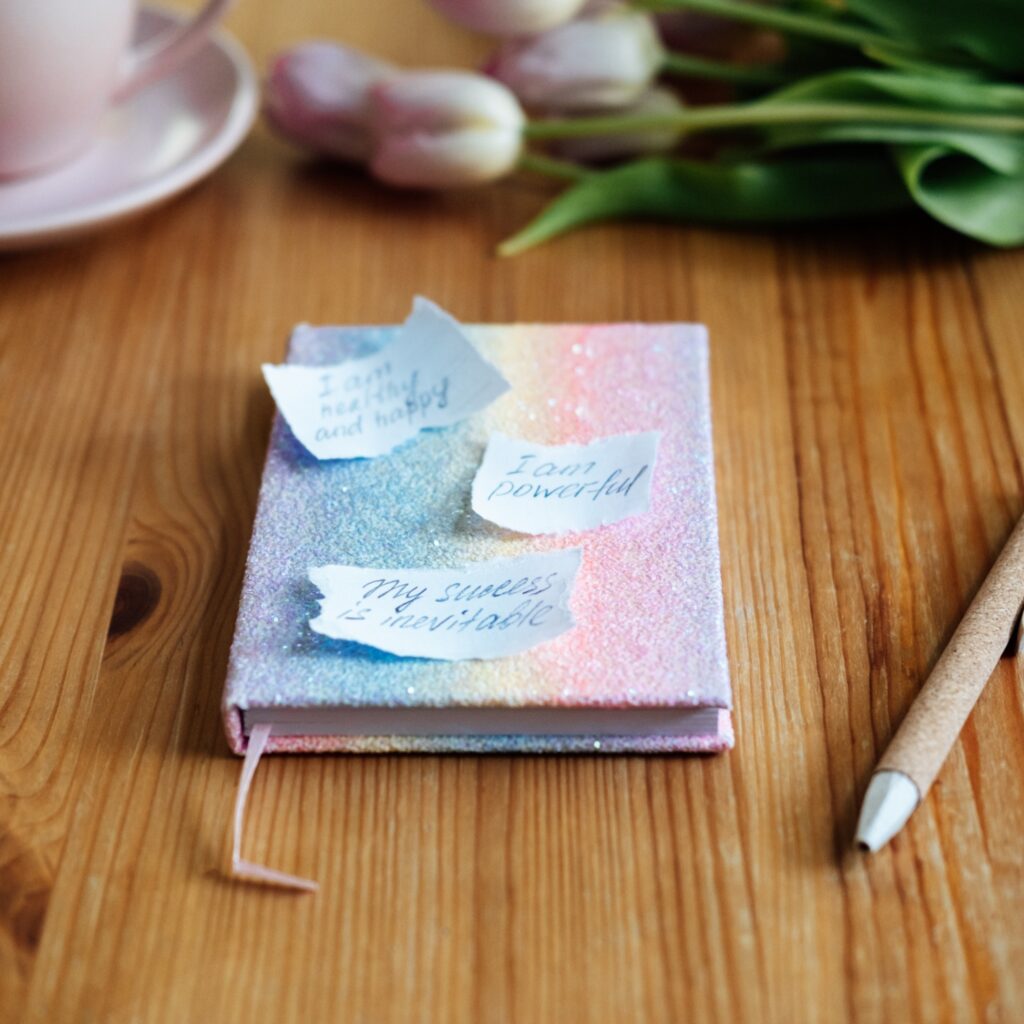 caderno rosa com post-its de afirmações positivas