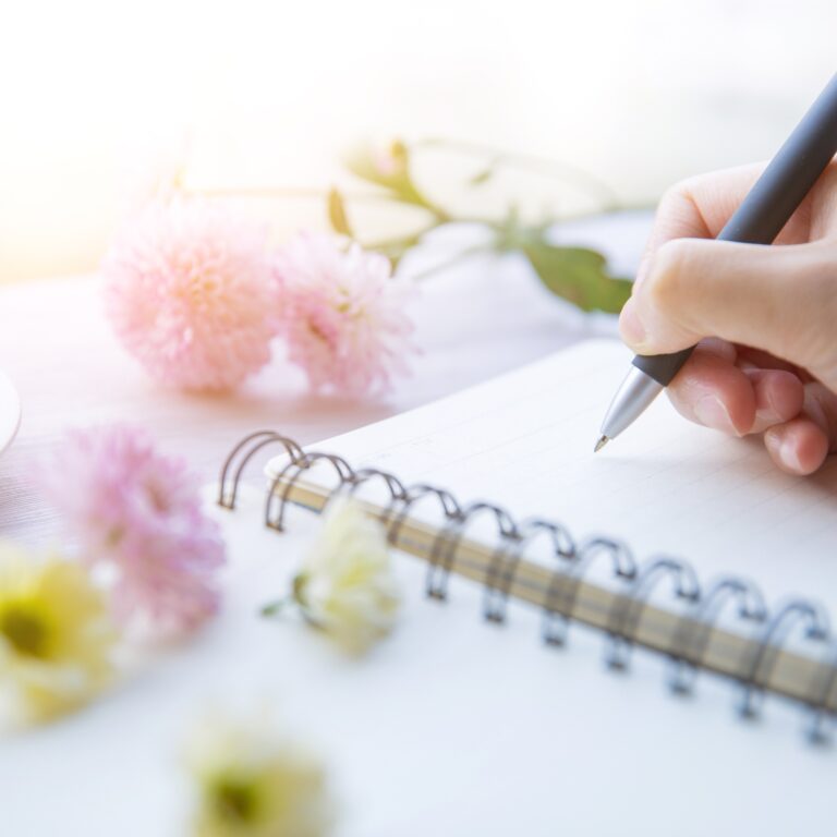 mão escrevendo em caderno com flores , uma escrita com florais