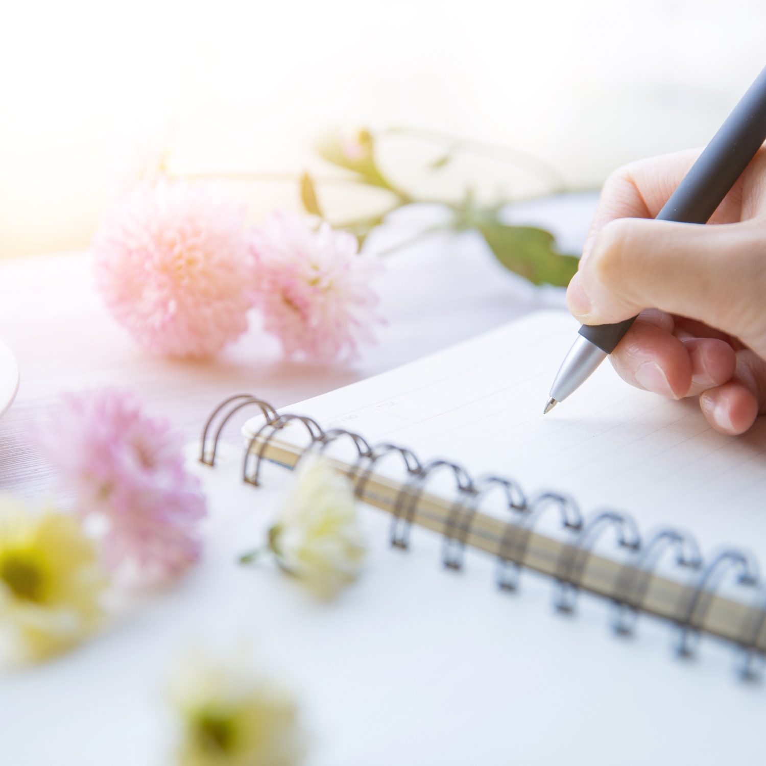 mão escrevendo em caderno com flores , uma escrita com florais